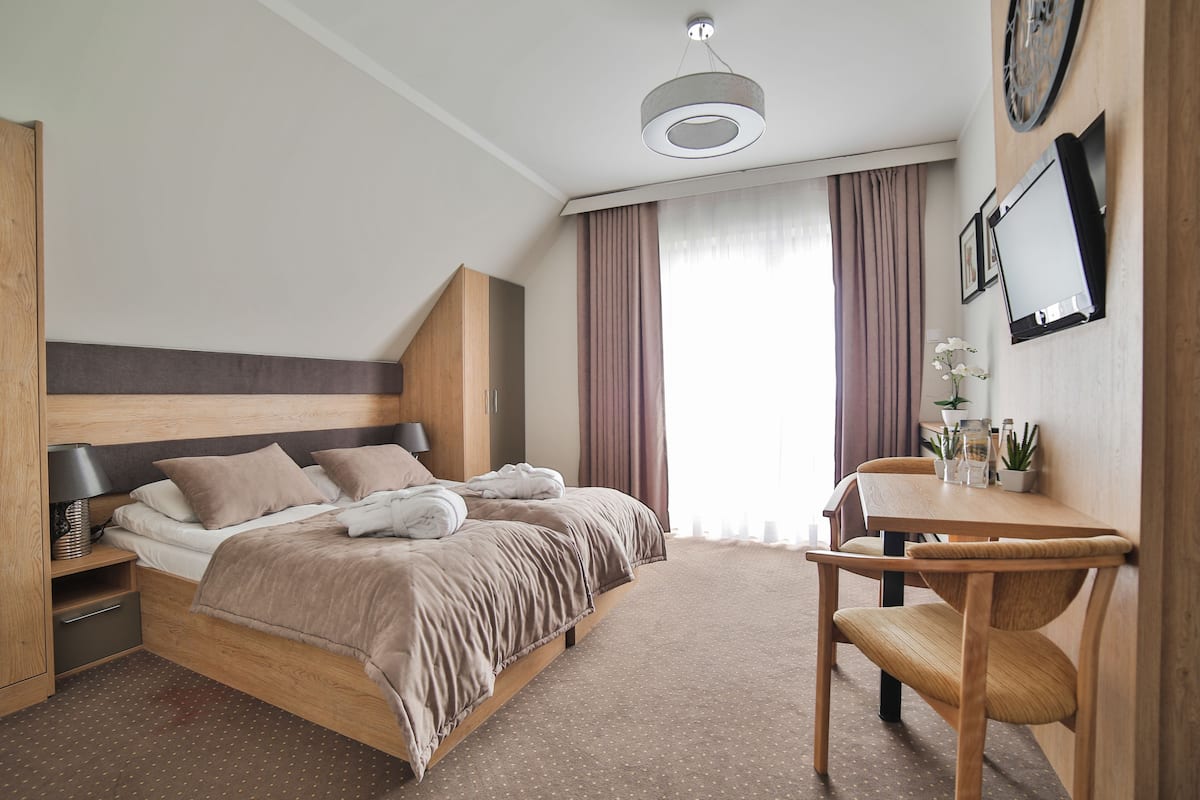 Una habitación de hotel moderna con una cama grande, un escritorio de madera y una silla.