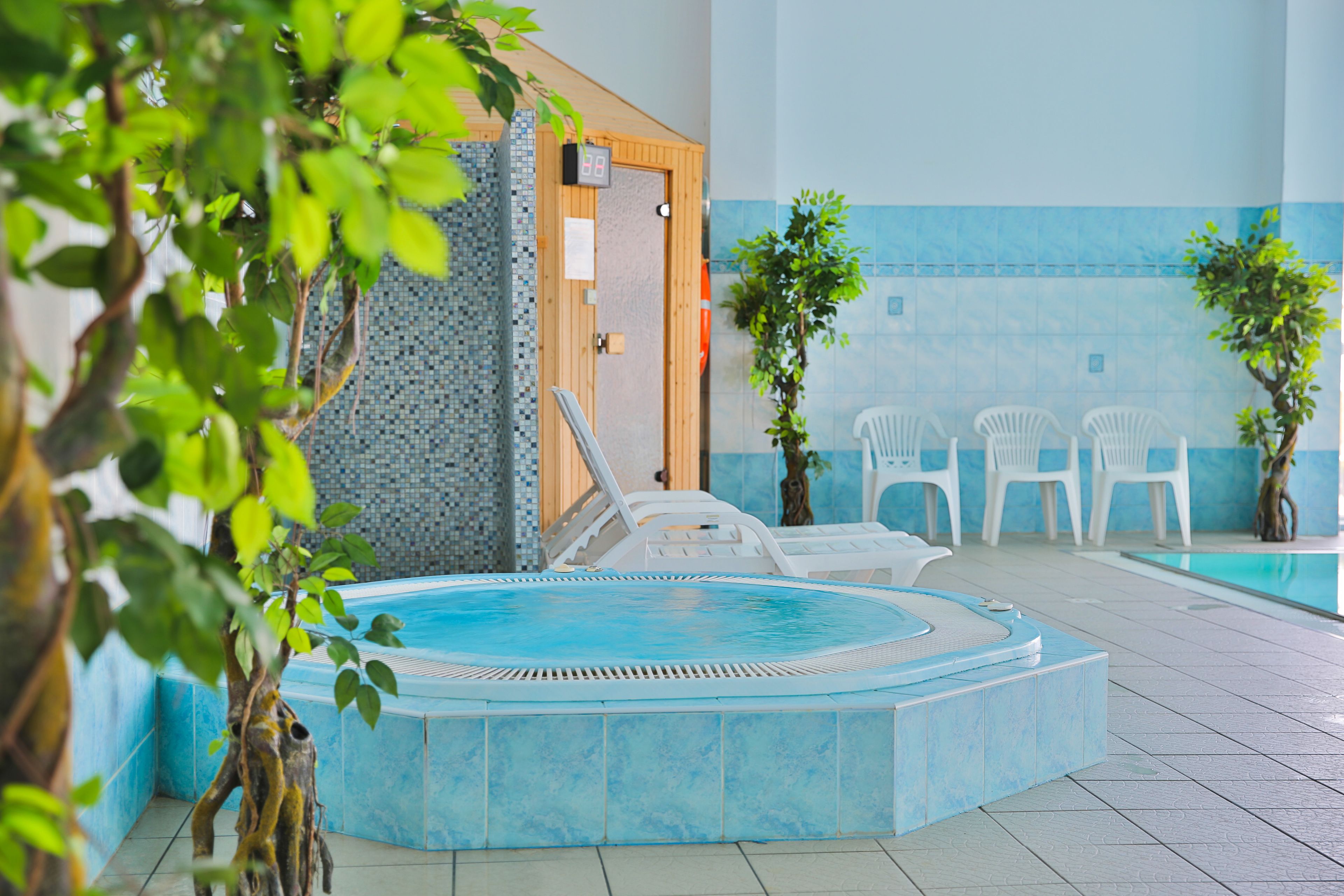A pool area with a hot tub, lounge chairs, and potted plants.