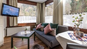 A cozy room with a sofa, a table, and a television mounted on the wall. - Gasthof Waldcafe (Mayrhofen)