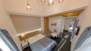 Una habitación de hotel con una cama, un sofá, una pequeña mesa con un florero y un espejo en la pared.
