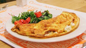 Un restaurante con un plato de comida en una mesa, que incluye una tortilla doblada, ensalada y un pequeño salero.