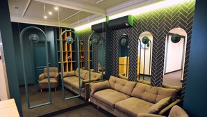Una habitación moderna con sofá, sillones y un espejo grande.