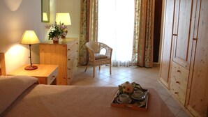 A cozy room with a bed, a wooden dresser, a chair, a lamp, and a tray with teacups and a teapot. - San Domenico Residence (Syracuse)
