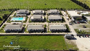 An aerial view of a resort with multiple buildings, a swimming pool, and surrounding green fields. - Calabernardo Resort (Noto)
