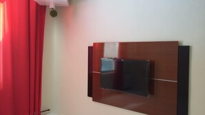 A modern room with a flat-screen TV mounted on a wooden panel wall. - Quartos em casa IN Caxias (Duque de Caxias)