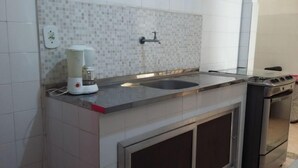 A kitchen with a tiled backsplash, a coffee maker, a sink, and a stove. - Quartos em casa IN Caxias (Duque de Caxias)