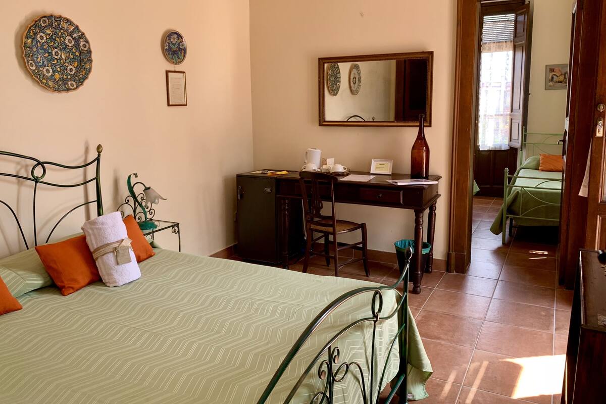 Une chambre à coucher comprenant un lit, un bureau, une chaise, une commode et un miroir.