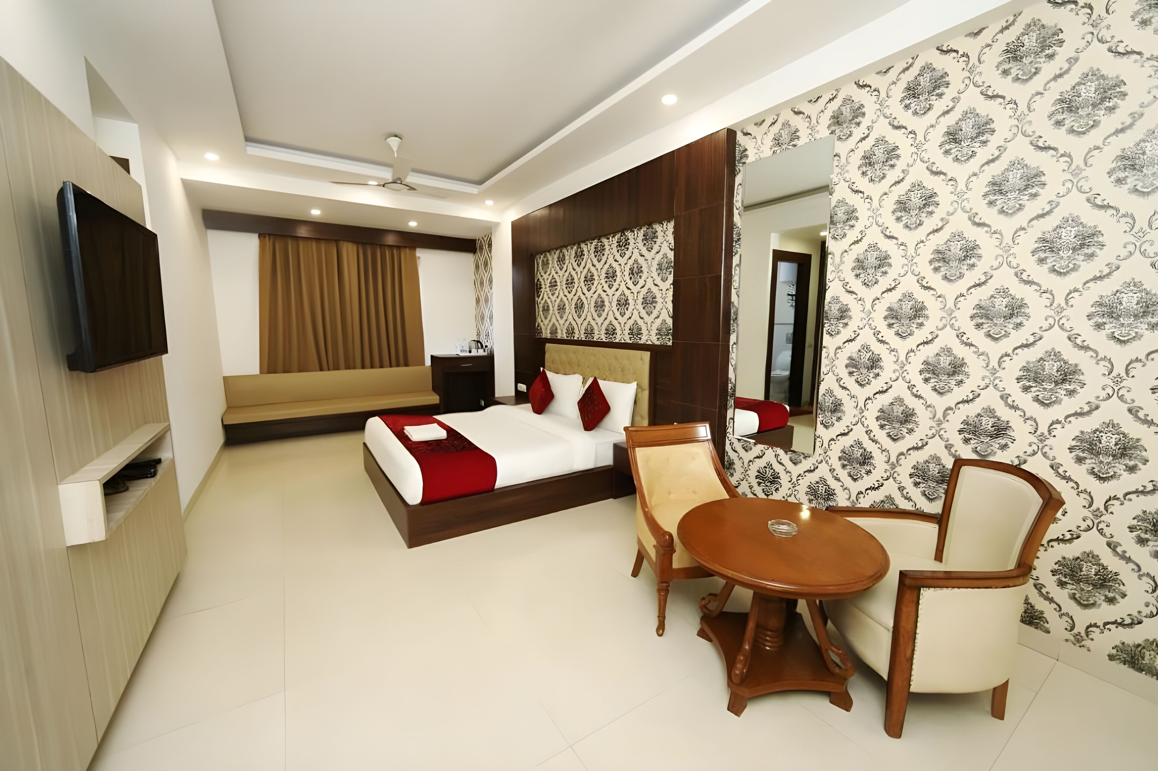 A modern hotel room with a bed, a TV, a dining table, and a chair.