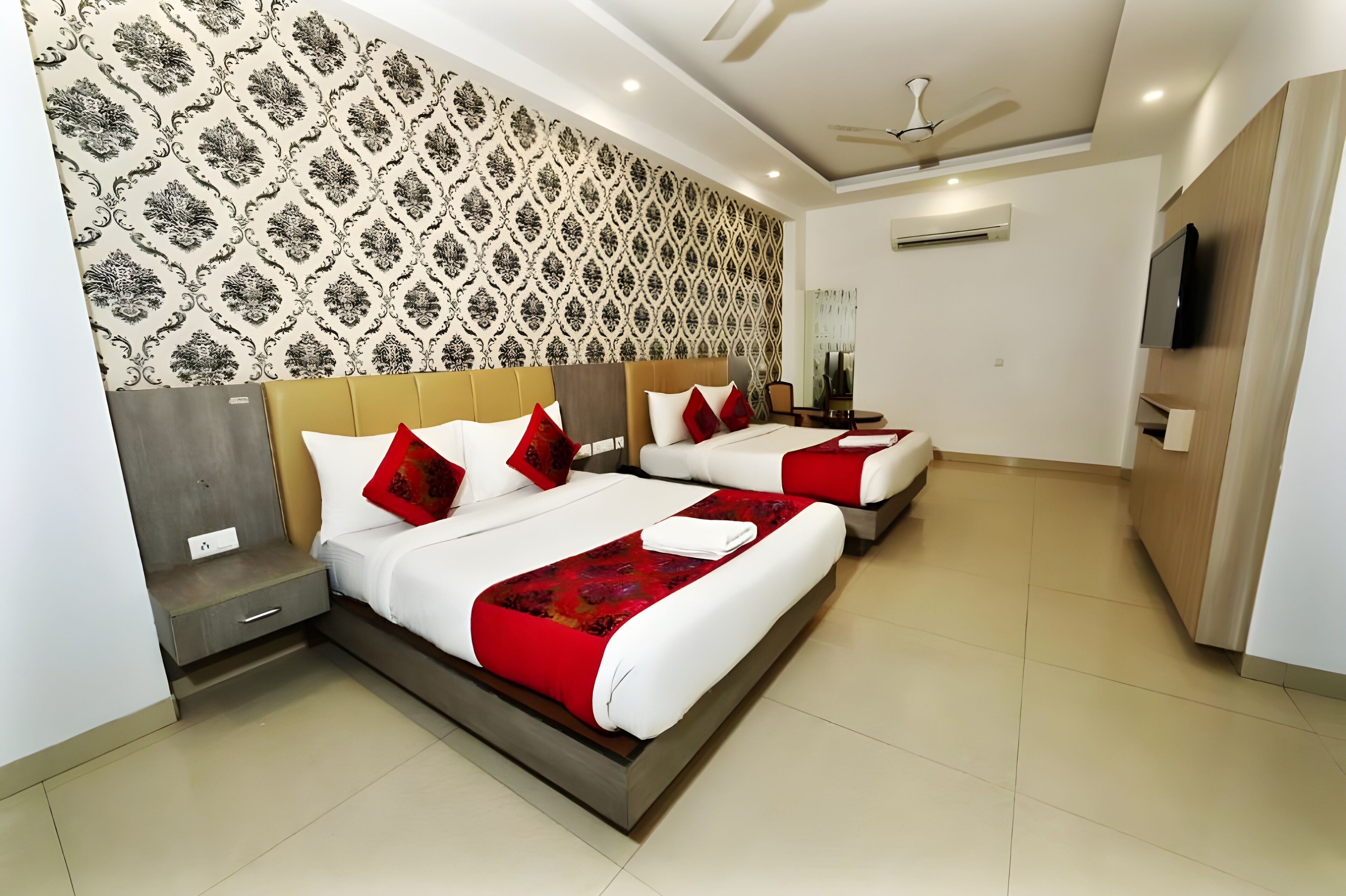 A hotel room with two beds, a TV, and a ceiling fan.