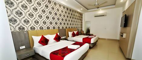 A hotel room with two beds, a TV, and a ceiling fan.