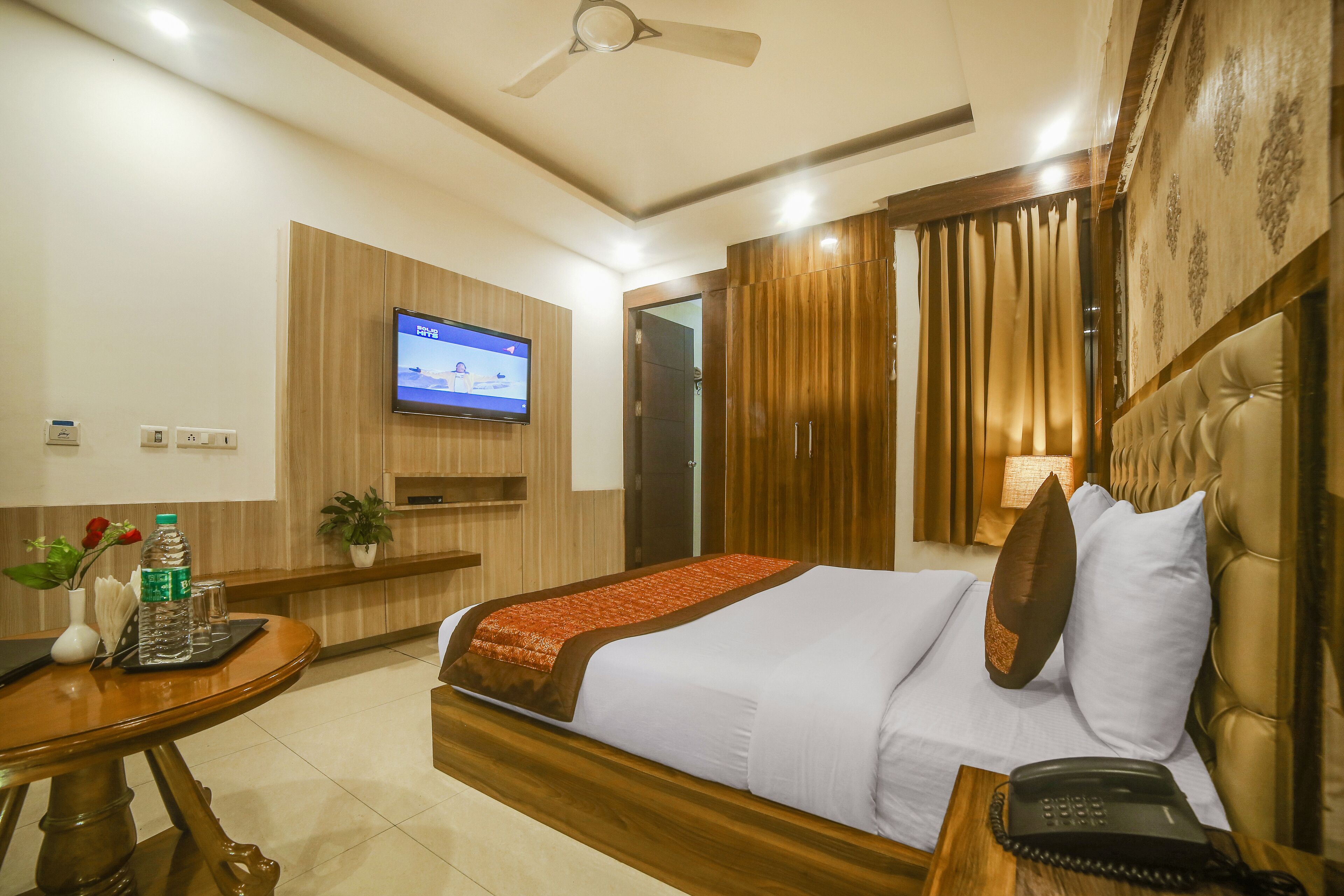 Una habitación de hotel con cama, mesita de noche, televisor y teléfono.