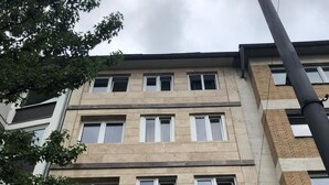 A multi-story hotel with a beige facade, multiple windows, and a visible "Hotel" sign. - Hotel Moji (Cologne)