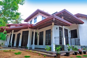 A two-story house with a covered porch, large windows, and potted plants. - Kottamba Yala Stay & Safari (Thissamaharama)