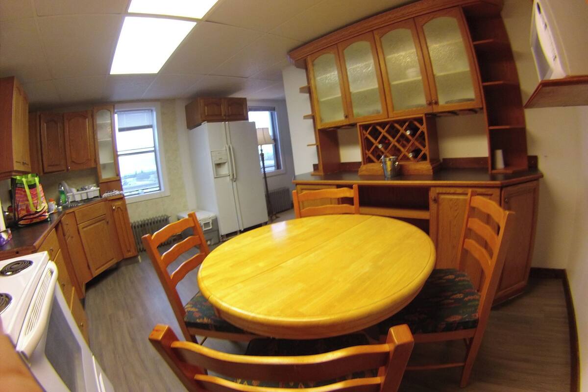 Una cocina compacta con armarios de madera, una isla central y una mesa de comedor con sillas.