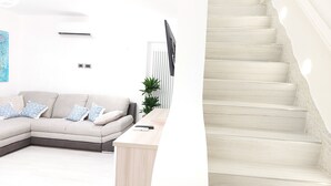 A modern living room with a light-colored sofa, a small table, and a staircase with white steps.