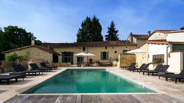 Relax by the rectangular pool surrounded by lounge chairs and a low stone wall.