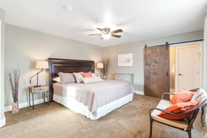 A bedroom with a bed, bedside tables, a chair, a ceiling fan, and a door.