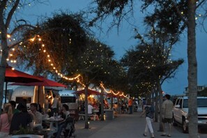 An outdoor dining area with string lights and umbrellas, surrounded by trees. - Luxury Living Along 30A-6 Seater Golf Cart/6 bikes! Next to Waterpark & Beach (Santa Rosa Beach)
