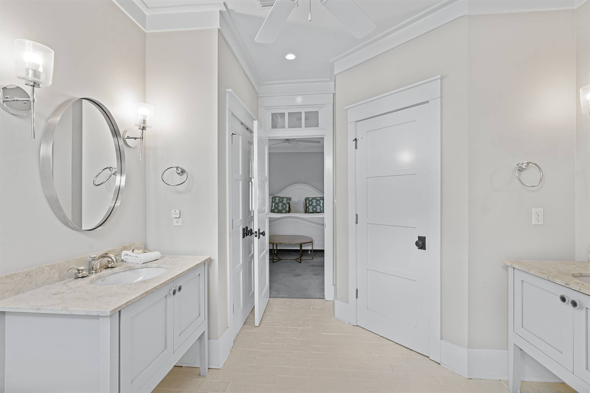 A modern bathroom with a large mirror, two sinks, and a walk-in closet.