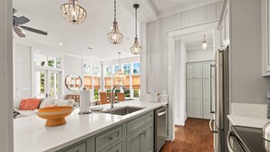 A modern kitchen with grey cabinets, a large island, stainless steel appliances, and pendant lighting. - Luxury Living Along 30A-6 Seater Golf Cart/6 bikes! Next to Waterpark & Beach (Santa Rosa Beach)