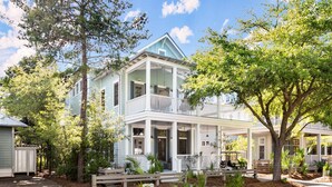 A two-story house with a porch, surrounded by trees and a brick pathway. - Luxury Living Along 30A-6 Seater Golf Cart/6 bikes! Next to Waterpark & Beach (Santa Rosa Beach)