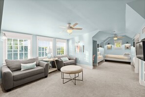 A spacious living room with a gray sofa, a round ottoman, and a ceiling fan. - Luxury Living Along 30A-6 Seater Golf Cart/6 bikes! Next to Waterpark & Beach (Santa Rosa Beach)