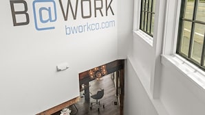 Un escalier avec une rampe en bois et un mur blanc orné d’un logo et de l’adresse d’un site web.