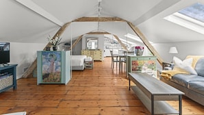 Un appartement-loft spacieux avec de hauts plafonds, des planchers en bois, un coin repas et un coin salon confortable.