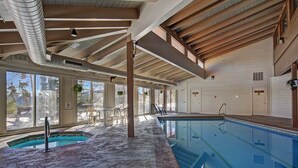 An indoor swimming pool with a tiled floor, wooden beams, and large windows. - Beautiful Condo, Sleeps 8, Gorgeous Views, Wood Fireplace, HDTV, Hot Tubs - BB (Silverthorne)