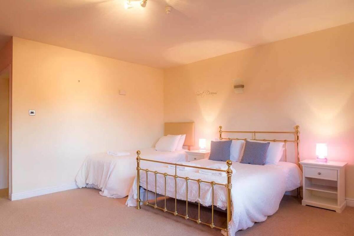 A bedroom with two single beds, a nightstand with a lamp, and a wall-mounted shelf.