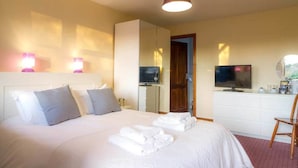 Ein Hotelzimmer mit einem Bett, einem Fernseher, einem Schreibtisch mit Stuhl und einem Spiegel.