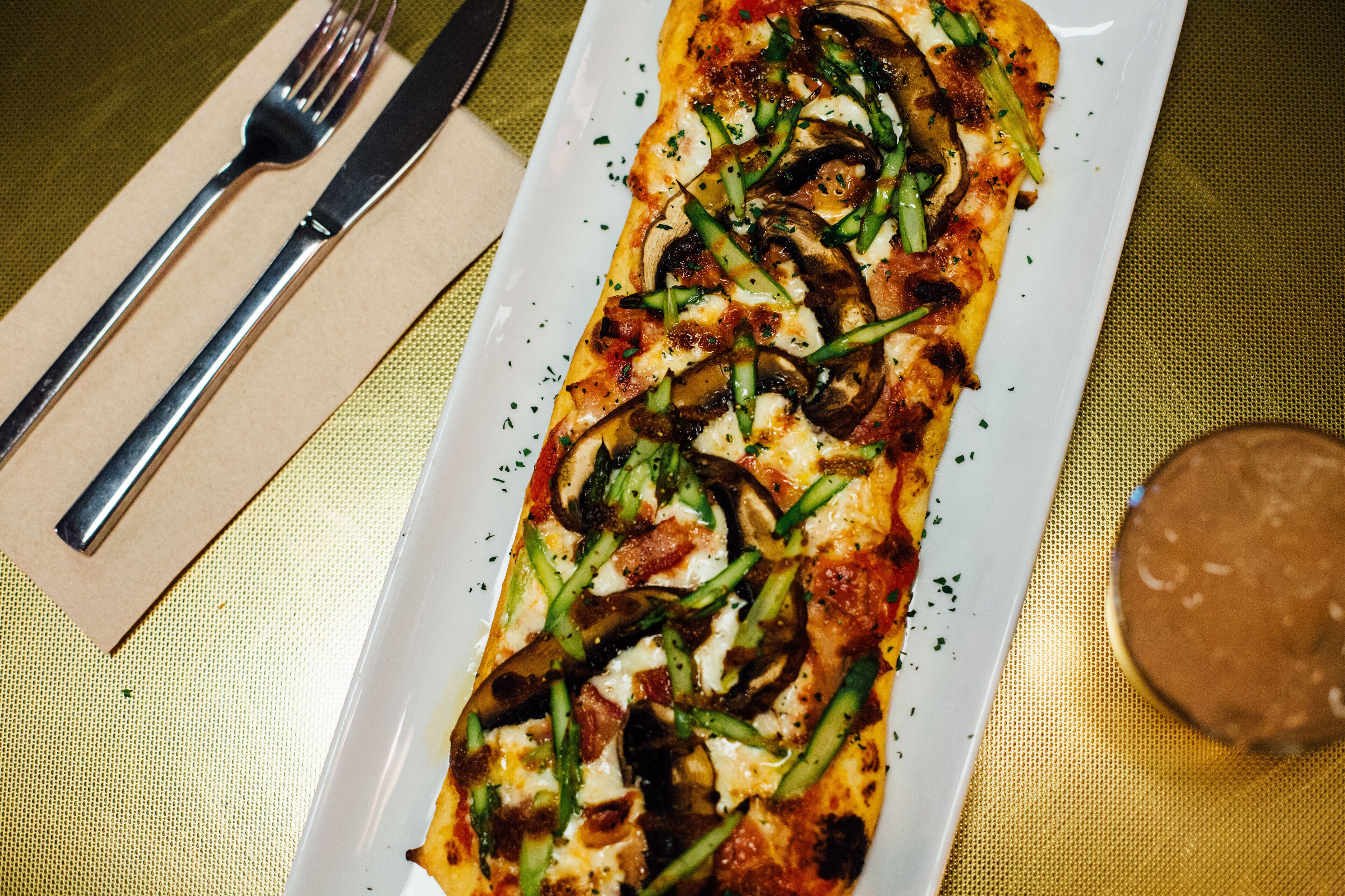 A rectangular pizza with toppings on a white plate.