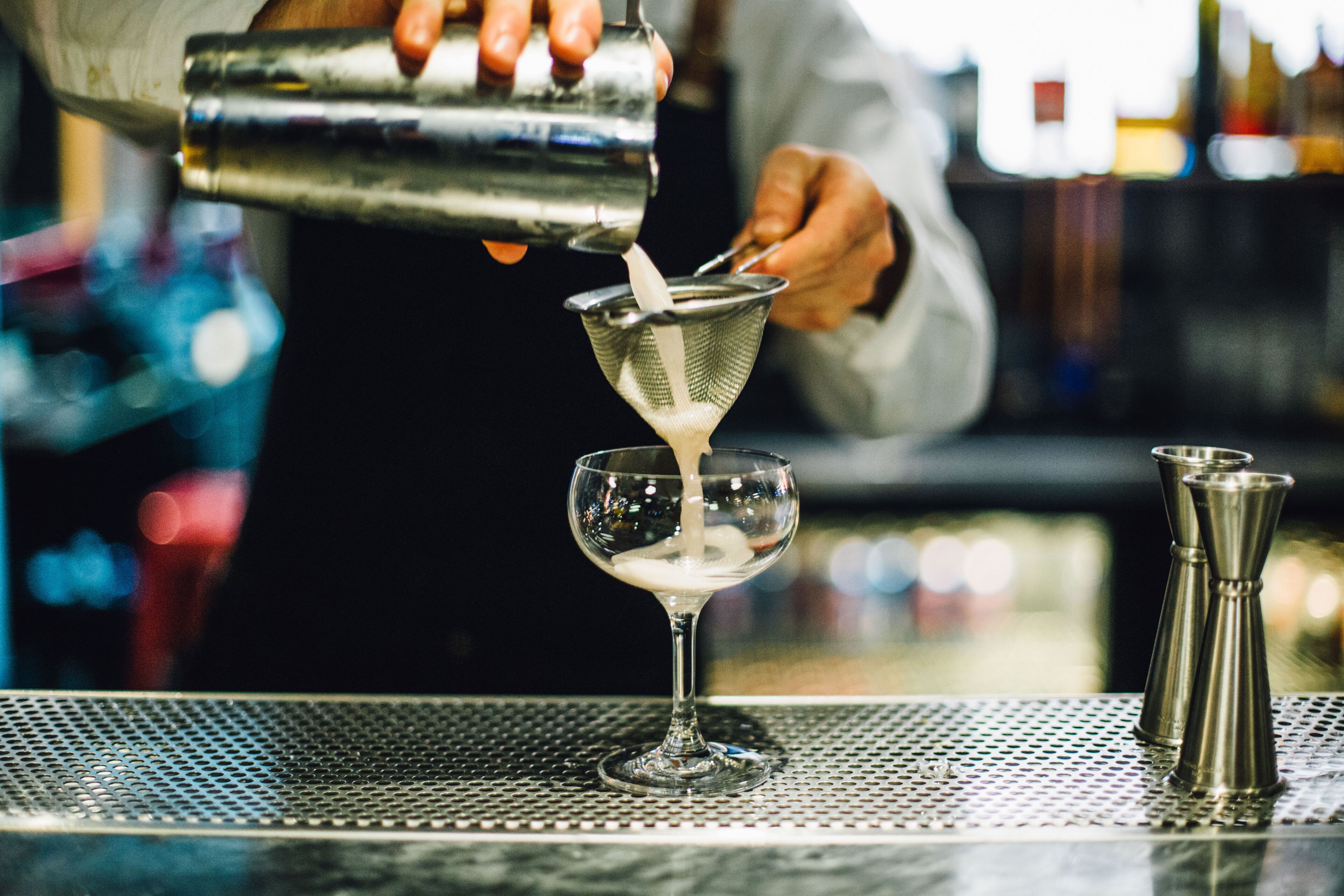 Un barman verse une boisson dans un verre à martini.
