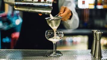 Un barman verse une boisson dans un verre à martini.