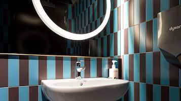 A bathroom with a white sink, a round mirror, and blue and brown checkered tiles.