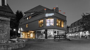 A two-story building with a sign reading "PANGEA POD HOTEL." It features large windows, a stone facade, and outdoor lighting. - Pangea Pod Hotel (Whistler)
