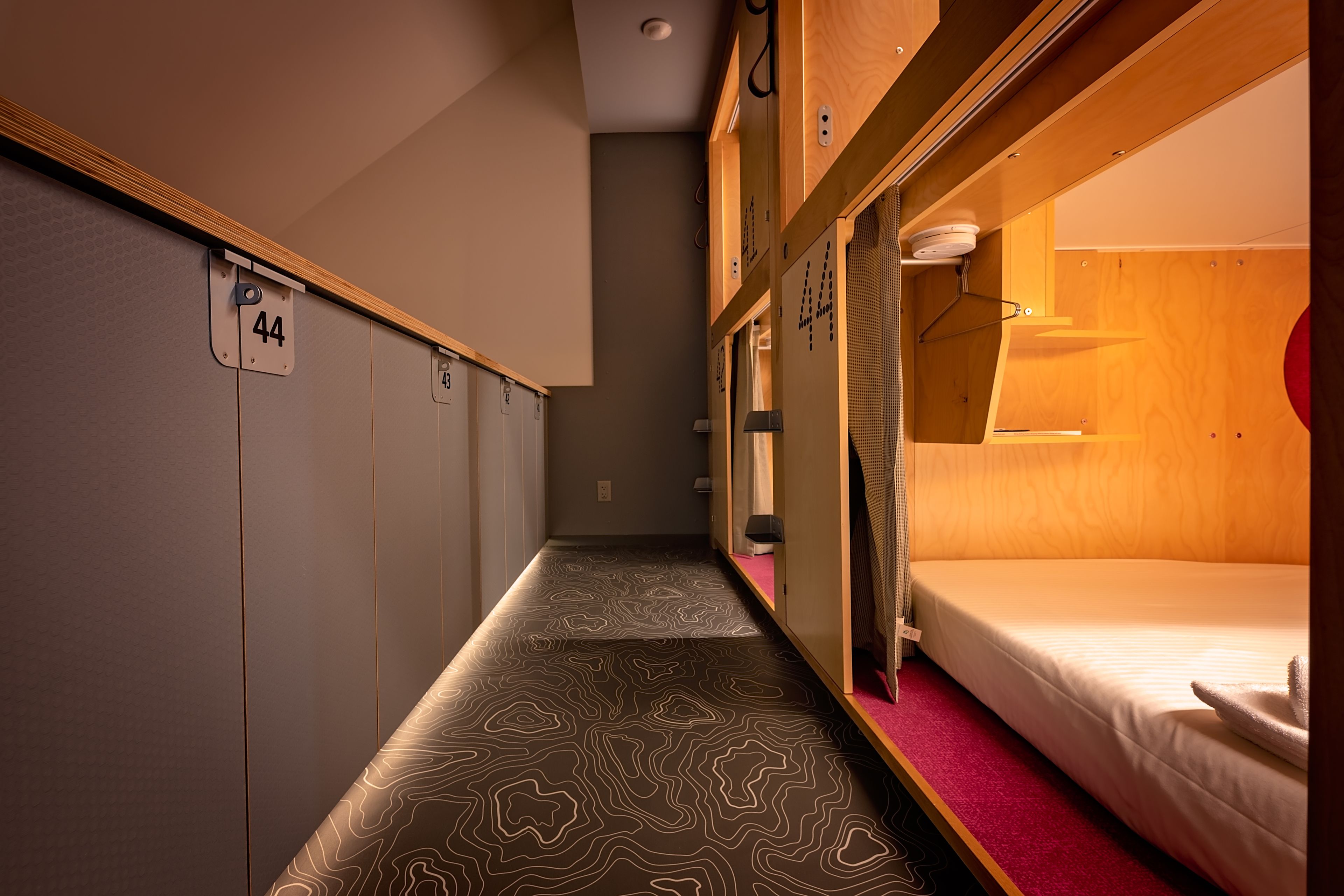 A narrow corridor with bunk beds on either side, each marked with a number.