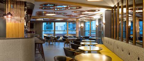 A modern restaurant interior with a bar area, round tables, and a seating arrangement.
