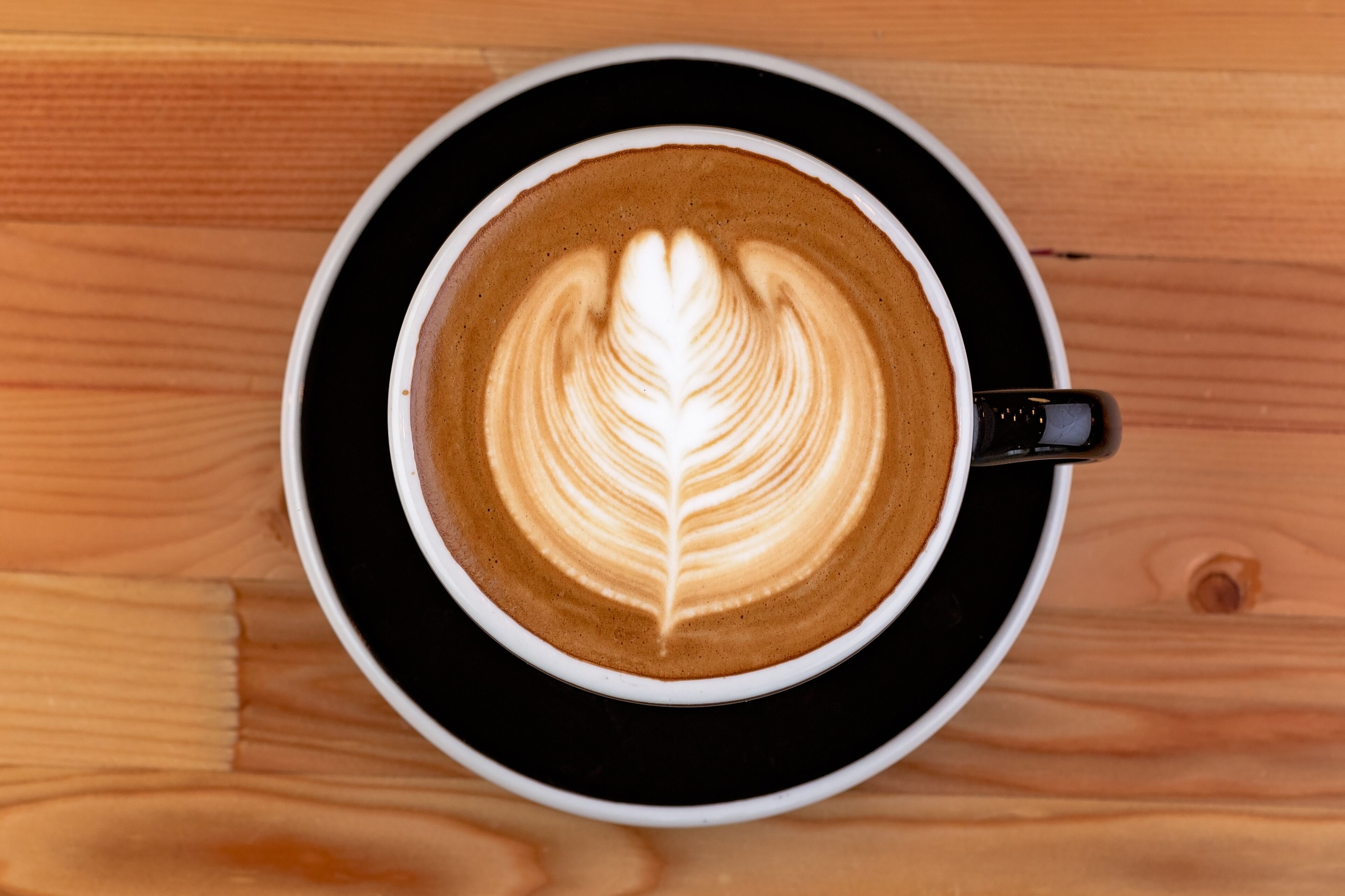Una taza de café con arte de latte sobre una mesa de madera.