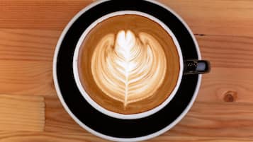 Una taza de café con arte de latte sobre una mesa de madera.