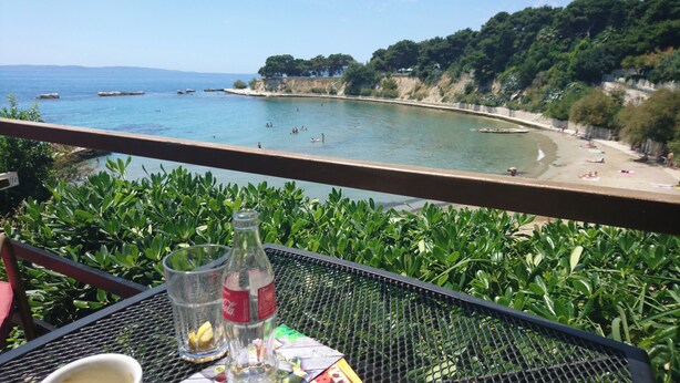 A balcony with a table, a bottle of Coca-Cola, and a glass of water. - Beach House Split (Split)