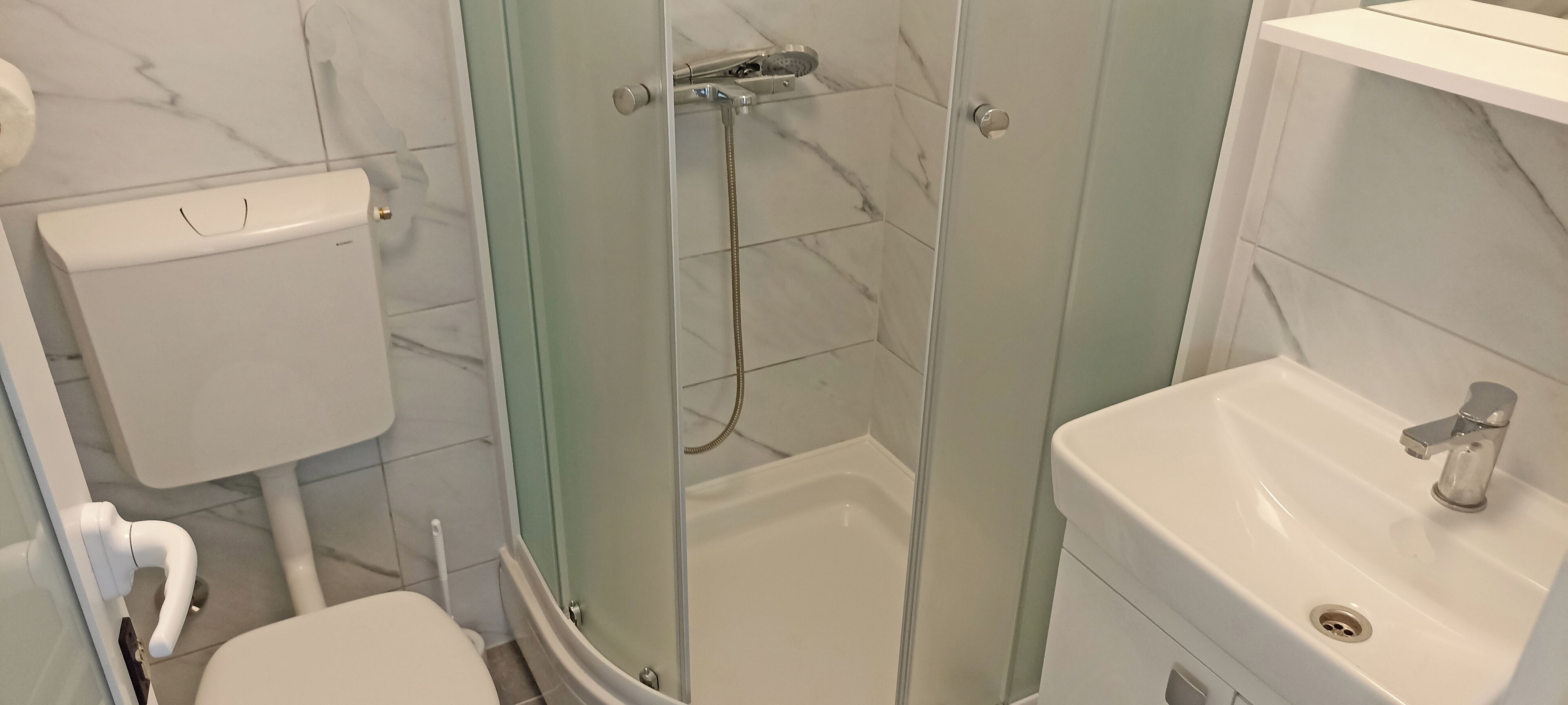 Ein Badezimmer mit Toilette, einer Duschkabine und einem Waschbecken.