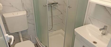 Ein Badezimmer mit Toilette, einer Duschkabine und einem Waschbecken.