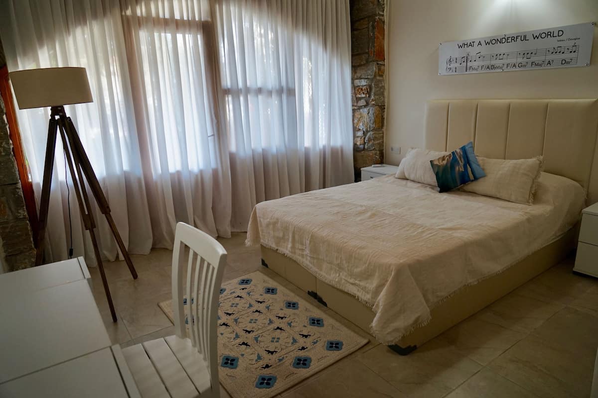 Een slaapkamer met een bed, nachtkastje, lamp en een muur met een poster.