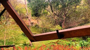 A wooden structure with a view of a garden with red flowers and trees. - Casa Fazenda Inglesa (Petrópolis)