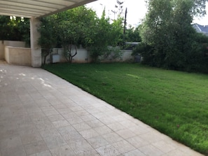 A covered patio area with a tiled floor and a grassy lawn. - Villa with Garden near Beach (Herzliya)