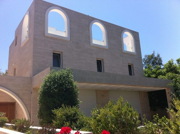 A modern building with three arched windows and a garage door. - Villa with Garden near Beach (Herzliya)