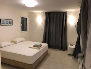 A bedroom with a bed, a window, a curtain, and a bedside table. - Villa with Garden near Beach (Herzliya)