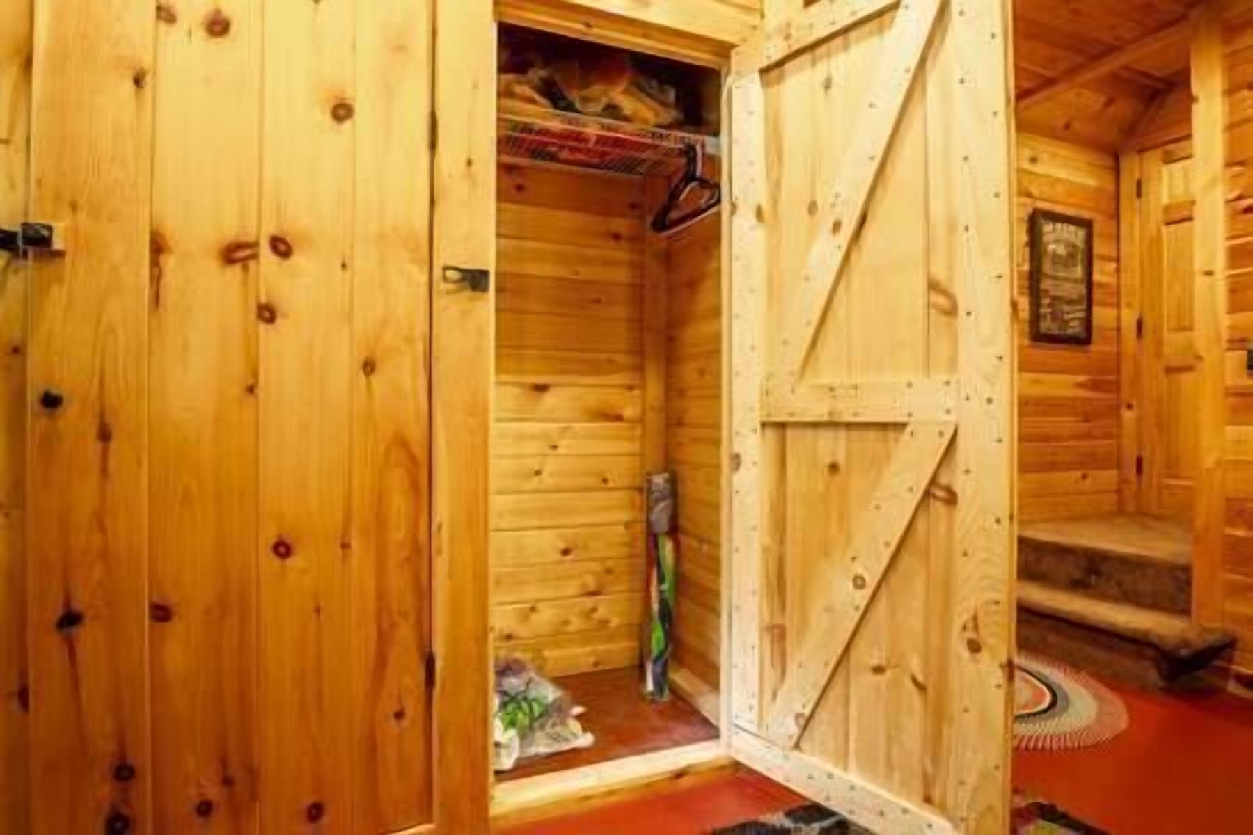 A wooden cabin with a large open door leading to a room with a red floor.