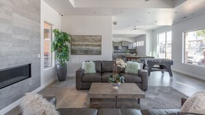 Ein modernes Wohnzimmer mit Kamin, einer Couch, einem Couchtisch und einem großen Fenster.